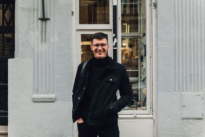 Portrait of smiling young man standing against store