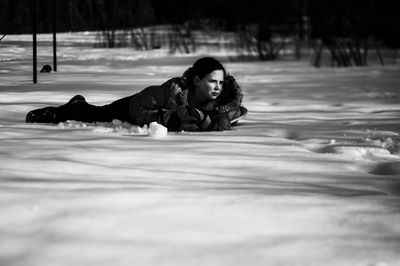 Side view of girl lying on snow covered field