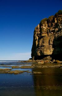 Rock formation on beach against clear blue sky