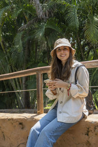 Beautiful young woman feeding a bird with a wooden stick with seeds stuck to it, bird stops to eat