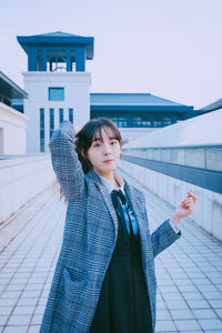 Portrait of beautiful young woman standing against building