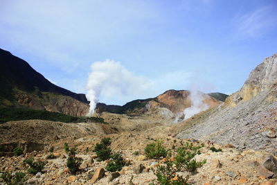 Panoramic view of smoke emitting from mountains against sky