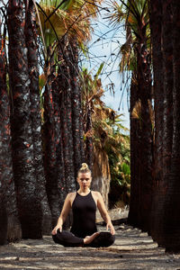 Full length portrait of woman sitting on plant against trees