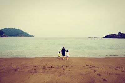 Rear view of people on beach against sky