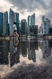 Reflection of man in swimming pool against buildings in city