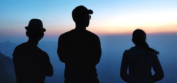 Silhouette people standing against sky during sunset