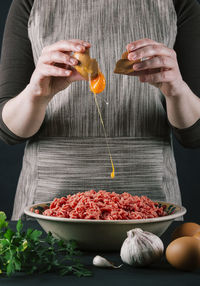 Female chef throwing an egg to flavor minced beef for cooking