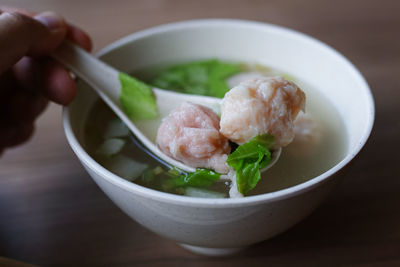 Close-up of hand holding soup in bowl