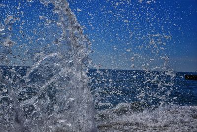 Water splashing in sea against blue sky