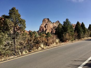 Road by trees against sky