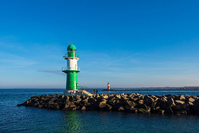 Lighthouse by sea against sky