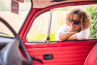 Woman smiling while leaning on car door