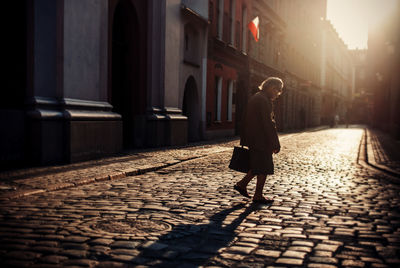 Side view of senior woman walking on cobblestone street