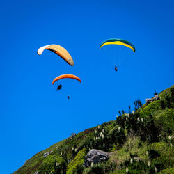 Low angle view of paragliding against clear blue sky