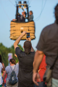 Rear view of man photographing while standing outdoors