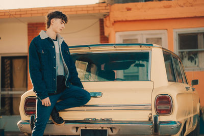 Fancy young man standing against vintage car