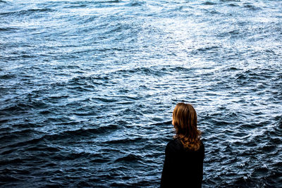 Rear view of woman standing by sea