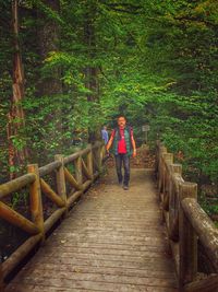 Woman standing on footbridge in forest