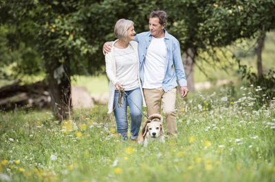 Rear view of man and woman with dog on grass