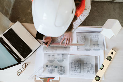 Top view of professional architect woman in construction site working on laptop and blueprints