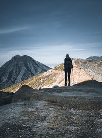 Rear view of woman walking on landscape against mountain