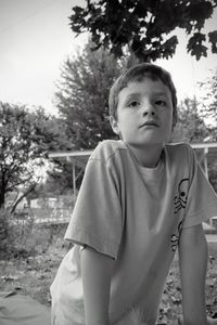 Cute boy looking away against trees