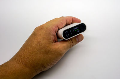 Close-up of hand holding smart phone over white background