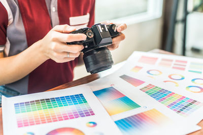 Midsection of design professional photographing color swatch on table