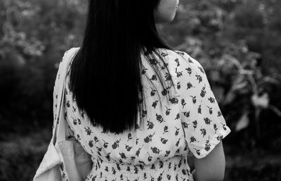 Rear view of woman standing against trees