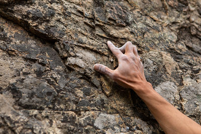 Midsection of human hand on rock