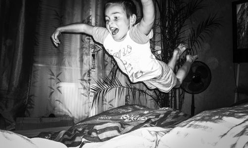 A boy jumping on bed at home