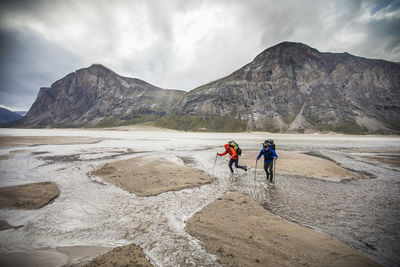 People on rocks against mountains