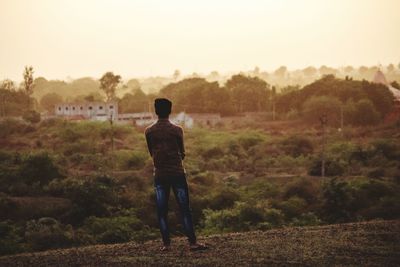 Rear view of man standing on field against sky