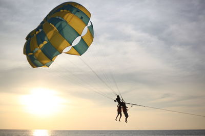 Low angle view of man paragliding in sea against sky