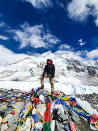 Full length of man standing on snowcapped mountain against sky