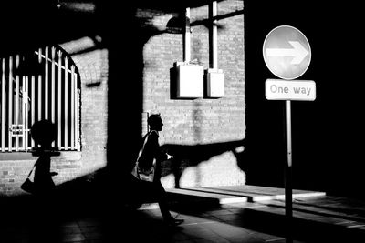 Silhouette man walking on footpath against building