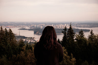 Rear view of woman looking at cityscape against sky