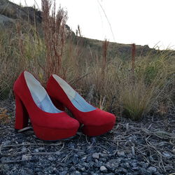 Low angle view of shoes on field against sky