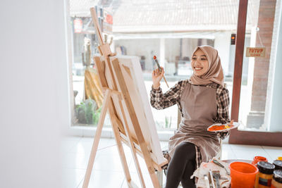 Smiling woman painting on canvas