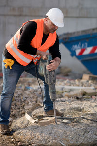 Worker drilling with jackhammer at construction site