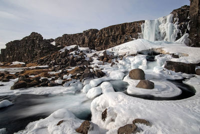 Rocks in sea against sky during winter