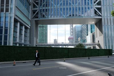 Man walking on street by modern buildings in city