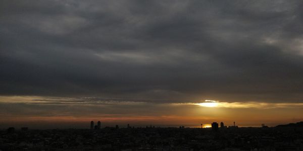 View of cityscape against cloudy sky during sunset