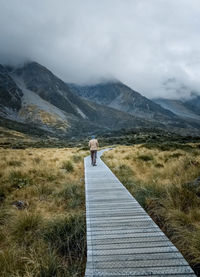 Rear view of person walking on footpath