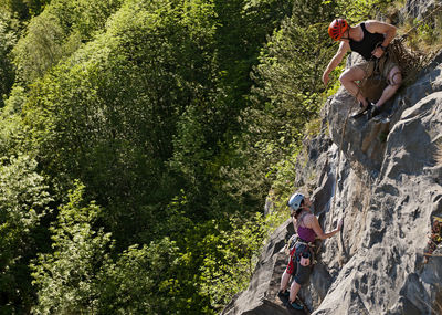 Couple climbing steep rock face in south wales