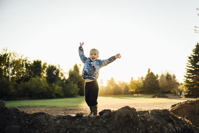 Cheerful boy with arms raised playing at park