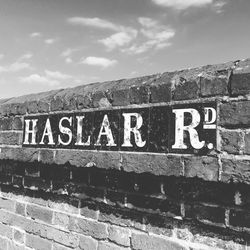 Text on brick wall against sky