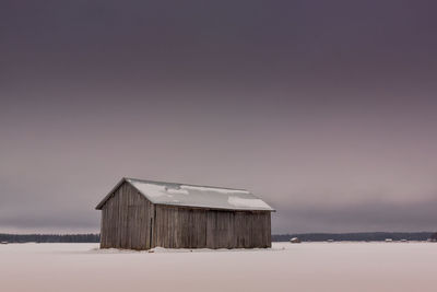 Barn on field against sky during winter