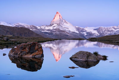 Reflection of snowcapped mountains on lake against clear sky