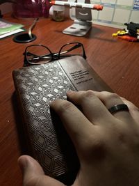 High angle view of hand holding book on table